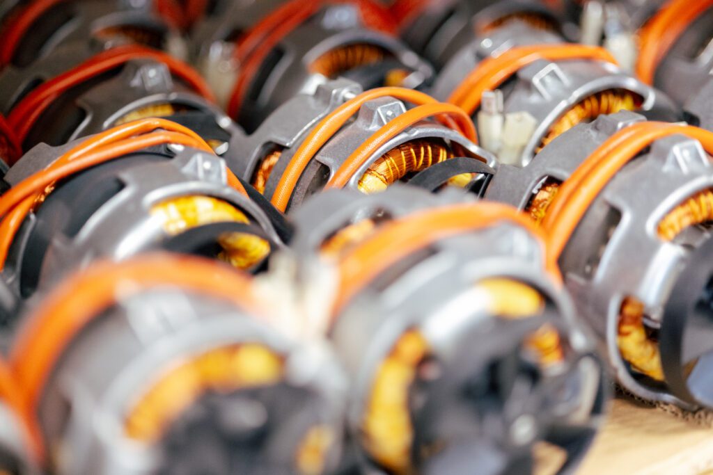 Nahaufnahme von mehreren Statoren mit Kupferwicklungen und orangefarbenen Kabeln – Elektromotoren-Komponenten in der Fertigung bei Witzel Vacupress