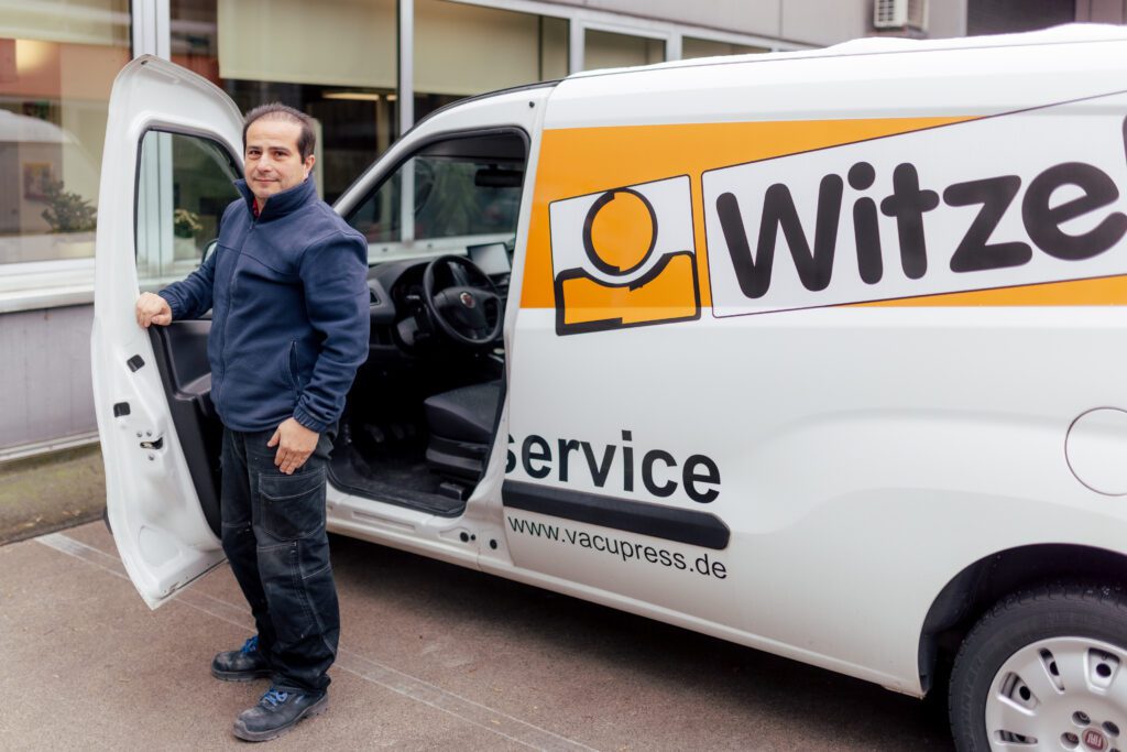 Mitarbeiter steht neben dem offenen Firmenwagen bei Witzel Vacupress