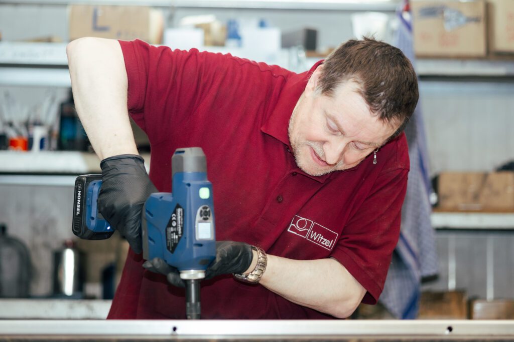 Mitarbeiter bearbeitet ein Werkstück in der Fertigung mit einer Bohrmaschine