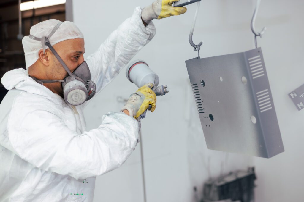 Mitarbeiter sprüht ein Werkstück bei Witzel Vacupress